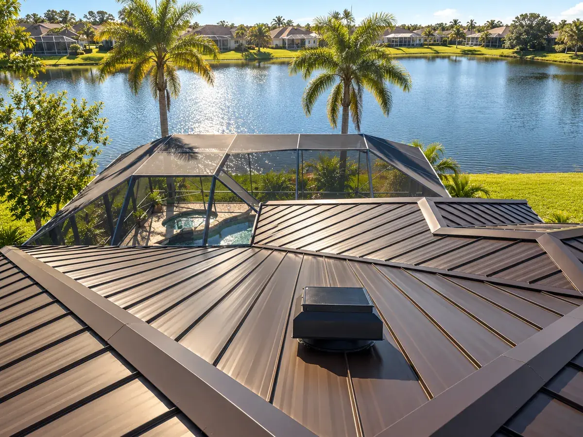 Standing-seam metal roof with a roof-mounted Attic Breeze solar attic fan, overlooking a waterfront neighborhood with palm trees