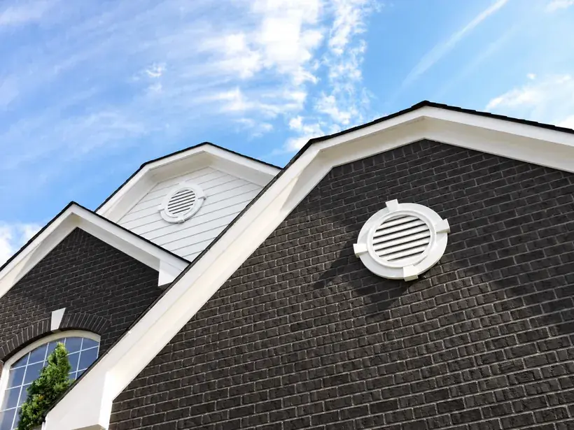 Brick home gable ends with round gable vents where a GableBreeze fan mounts behind the vent