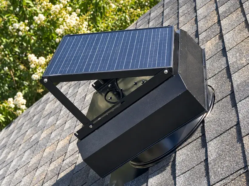UltraBreeze solar attic fan installed on a shingle roof, with its raised solar panel angled toward the sun